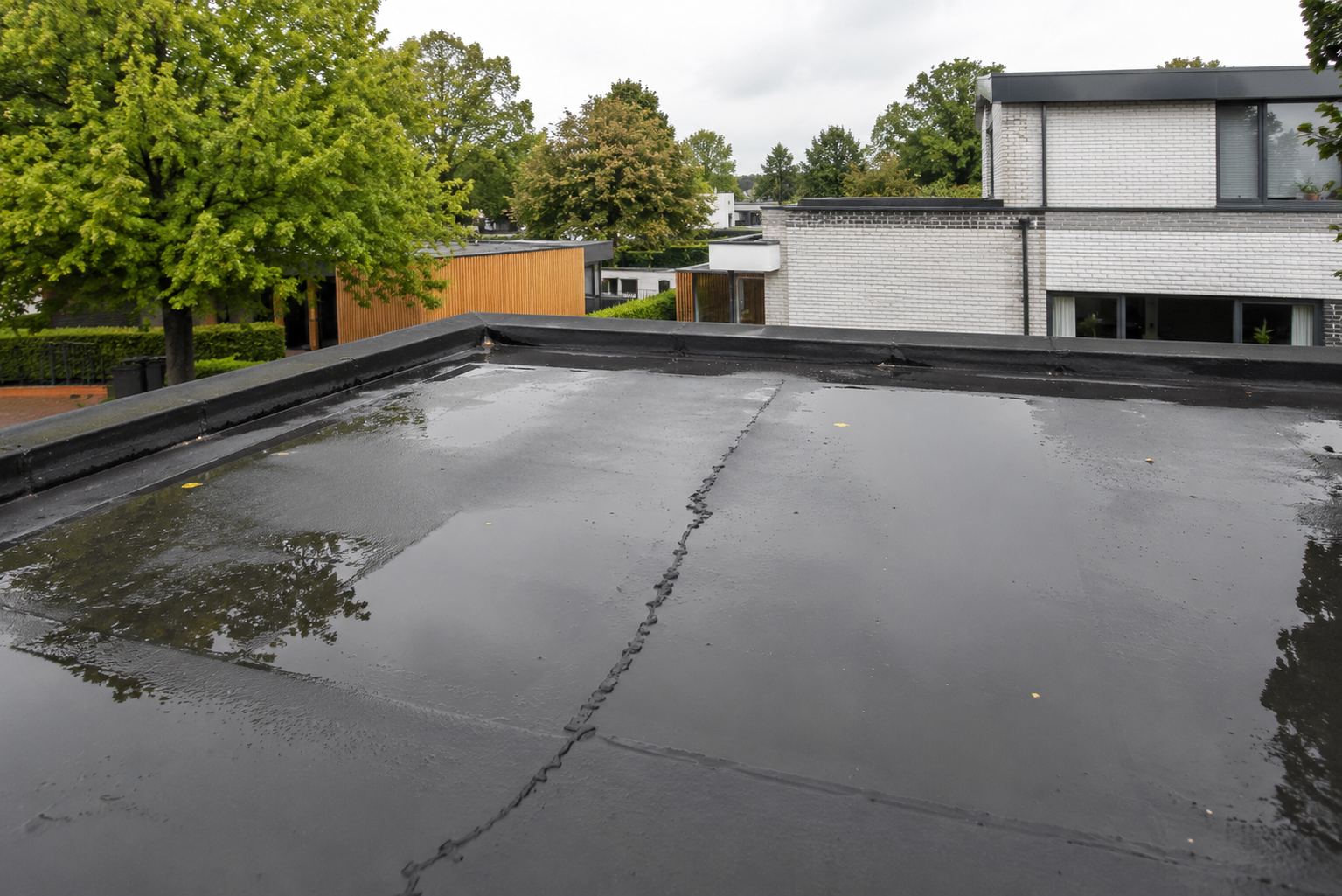 Beschadigde bitumen dakbedekking op een plat dak met risico op lekkage