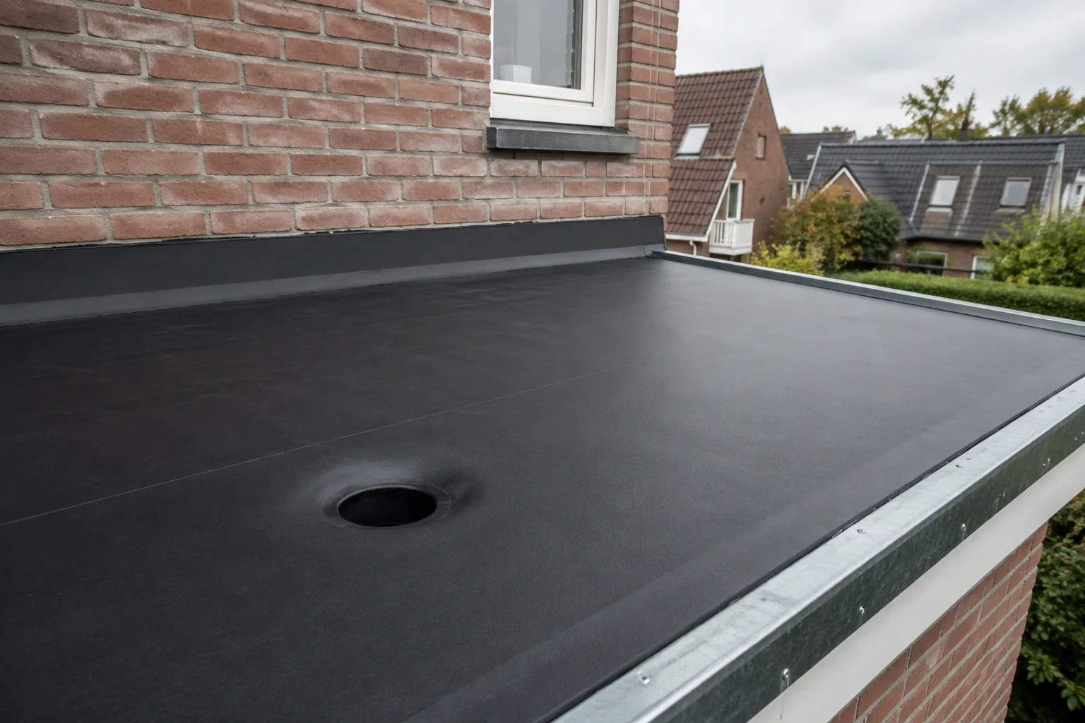 Plat dak met zwarte EPDM dakbedekking, een verlijmde dakrand en een hemelwaterafvoer