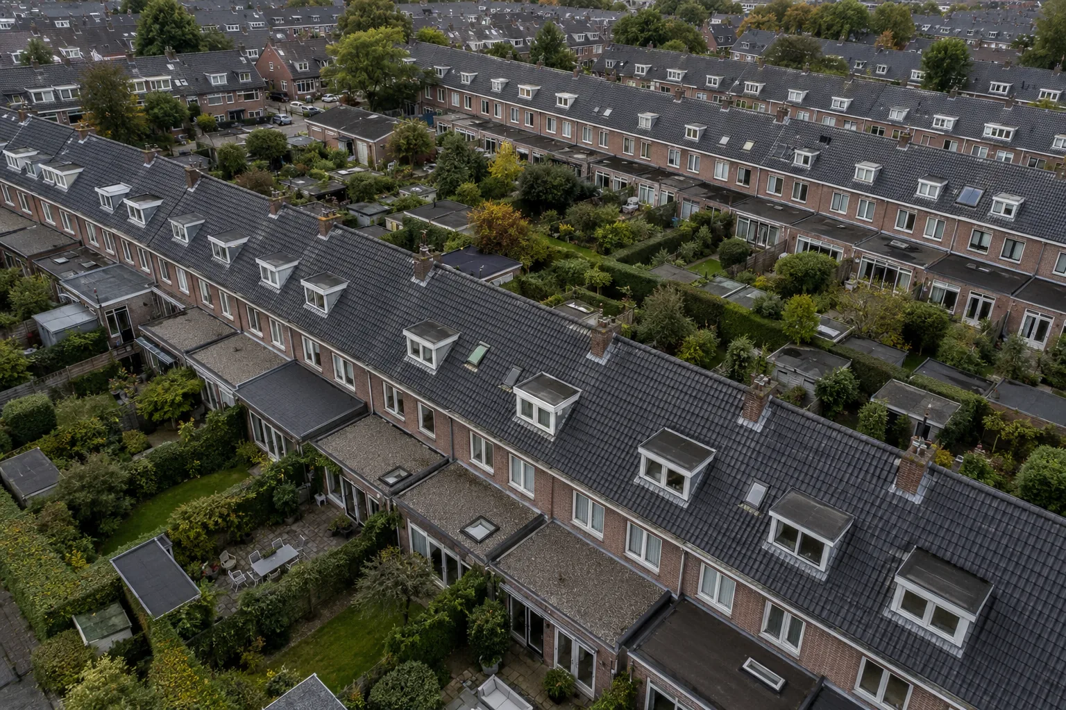 Nederlandse woonwijk van bovenaf met rijen pannendaken, platte uitbouwen en dakkapellen